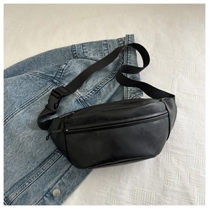 Close-up of black litchi pattern leather chest bag with zipper on denim jacket