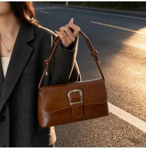 Detail of dark brown leather baguette bag with silver buckle and knotted shoulder strap