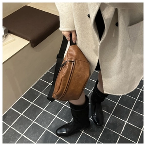 Detailed view of brown faux leather chest bag showing soft lychee texture and zipper