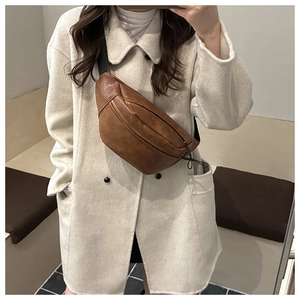 Brown vintage PU leather chest bag with reinforced stitching on white winter coat