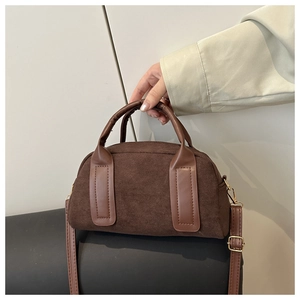 Macro scatto della borsa Boston in camoscio marrone con manici in pelle e dettagli dorati