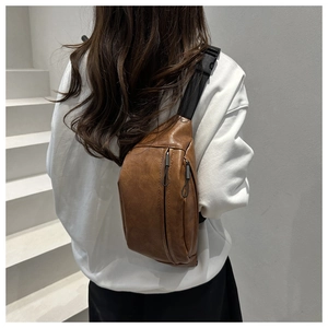 Brown lychee texture leather chest bag shown on model in a modern indoor setting