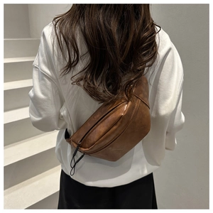Rear view of model wearing a vintage brown matte saddle bag with black wide straps