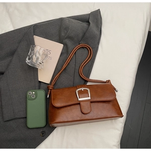Top-down view of a vintage brown baguette bag with silver buckle and cord strap details