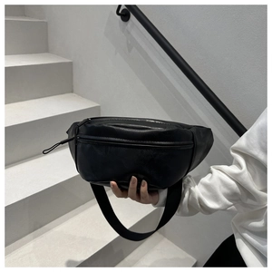 Close-up of black PU leather chest bag with lychee texture on white minimalist stairs