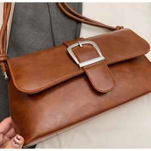 Detail of caramel brown baguette bag featuring grainy leather texture and silver buckle
