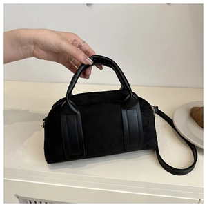 Dettaglio della borsa Boston in camoscio nero con manici in pelle liscia e cerniera metallica