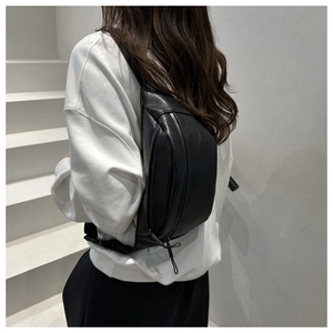 Rear view of a minimalist black PU leather crossbody bag worn across the back by a model