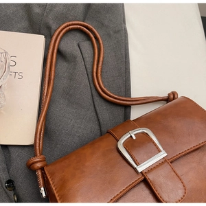 Detail of vintage brown leather baguette bag featuring a large silver square buckle