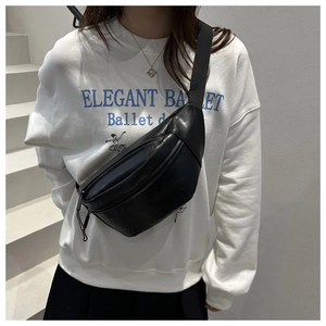 Detail of minimalist black PU leather chest bag with adjustable strap and metal zipper