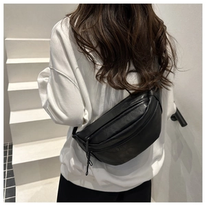 Detail of black semi-circle crossbody bag with textured faux leather and zip closure