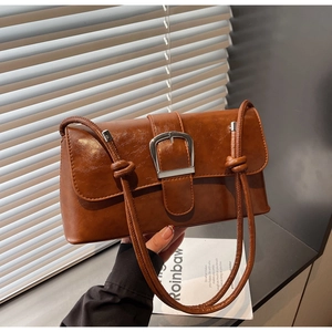Detailed shot of retro brown leather bag featuring large silver buckle and knotted strap