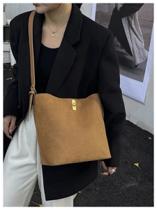 Detail of brown suede shoulder bag with gold metal twist lock and adjustable strap