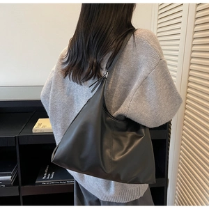 Minimalist large black hobo shoulder bag with soft leather texture on knit sweater