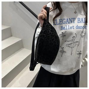 Close-up of black leopard print crossbody bag with adjustable wide nylon shoulder strap
