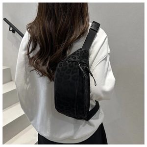 Close-up of black leopard print crossbody bag with adjustable strap on a model