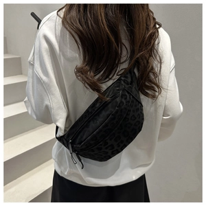 Detail shot of black leopard print crossbody bag worn as a chest bag in a modern setting
