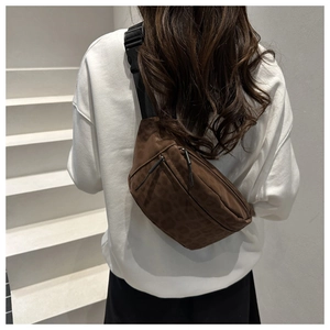 Detailed view of the leopard print crossbody chest bag worn by a model on a white background