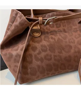 Detail of leopard print fabric texture and silver metal buckle on brown shoulder bag