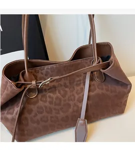 Detail shot of large leopard print tote bag with brown suede texture and long leather straps