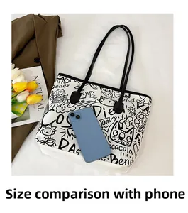 Close-up of graffiti canvas tote bag with black straps beside a blue smartphone