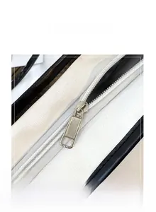 Detailed macro view of the smooth silver metal zipper on the black and white handbag