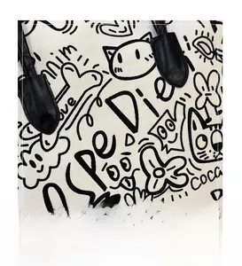 Detailed macro view of graffiti printed canvas bag with reinforced leather handles