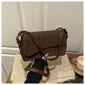 Detail of dark brown faux suede crossbody bag with leopard pattern and leather strap