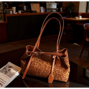 Close-up of leopard print tote bag with brown leather strap on a cafe table
