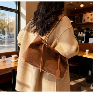 Detail view of brown suede tote bag with leopard texture and decorative tassels
