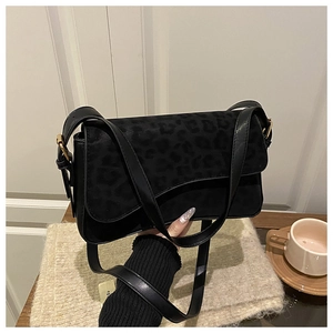 Detail of black crossbody bag featuring leopard print flap and gold metal hardware