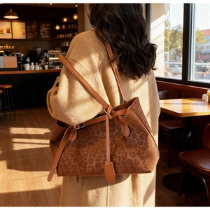 Detailed view of large leopard print tote bag on shoulder in a warm cafe lighting