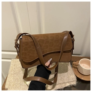 Detail of vintage leopard print suede flap and brown leather crossbody bag held by hand