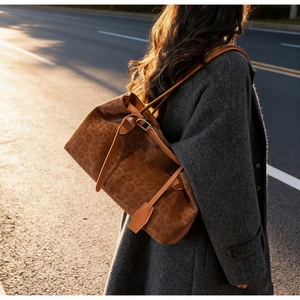 Outdoor close-up of leopard print tote bag with brown straps on model in golden light
