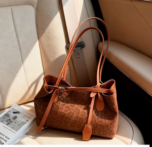 Macro view of leopard print tote bag with brown leather straps on a car seat