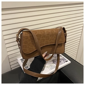 Detail of a brown crossbody bag featuring a leopard print flap and gold buckle closure