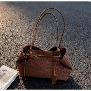 Detail of leopard print tote bag with thin shoulder straps on asphalt in golden hour light
