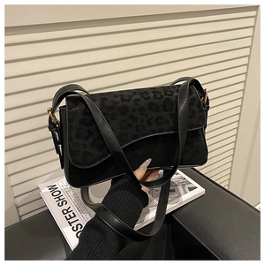 Close-up of black leopard print patchwork handbag with smooth faux leather and gold buckle