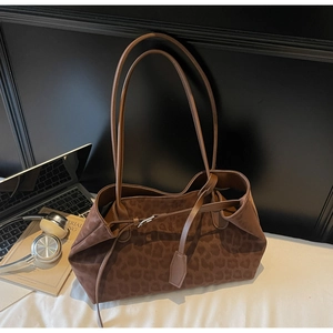 Leopard print tote bag with shoulder straps and buckle detail in a workspace setting