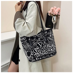 Detailed close-up of a black tote bag featuring white graffiti prints and long handles