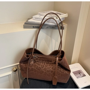 Close-up of leopard print tote bag with long shoulder strap on a minimalist background