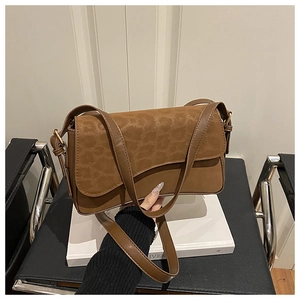 Close-up of vintage brown leather handbag featuring a leopard print flap on books