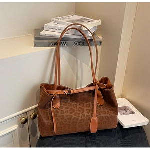 Detail of leopard print tote bag featuring matte texture and adjustable buckle strap