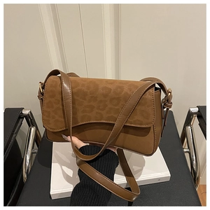 Detail of a brown crossbody bag with a leopard print suede flap and golden metal hardware