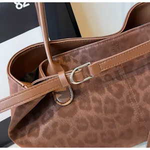 Macro shot of faux suede leopard print tote bag with silver metal buckle detail