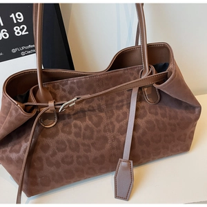Close-up of leopard pattern texture and long leather pendant on dark brown tote bag