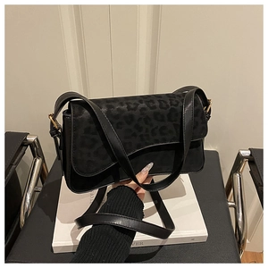 Detail of black faux leather shoulder bag with leopard print suede flap and gold hardware