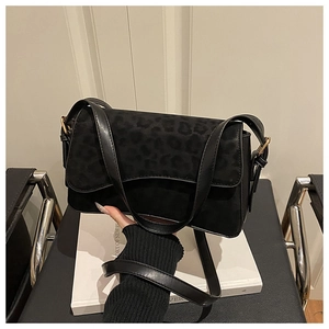 Close-up of black leopard print suede flap and smooth leather texture on women's shoulder bag
