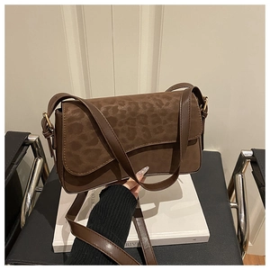 Detail of a brown crossbody bag featuring a leopard print flap and gold-tone hardware