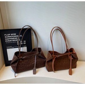 Detail of leopard print tote bags in dark brown and caramel suede with buckle accents